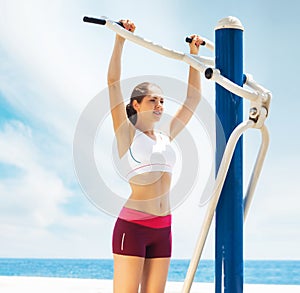 Young and sporty woman training in outdoor gym. Fitness, sport and health care.