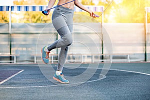 Young sporty woman training with skipping rope on stadium