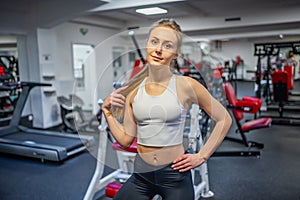 Young sporty woman wearing sportswear posing before doing exercise with fitness equipment at gym, she exercise for