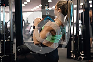 Young sporty woman working at the lat pulldown machine in the gym.
