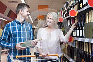 Young spouse buys wine in the store