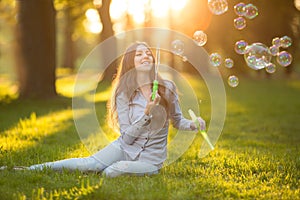 Young spring fashion casual woman blow bubbles in the sunset in