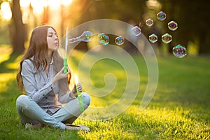 Young spring fashion casual woman blow bubbles in the sunset in