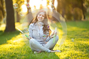 Young spring fashion casual woman blow bubbles in the sunset in