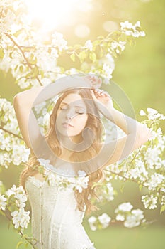 Young spring fashion woman in spring garden Springtime Summertime Trendy girl in the flowering trees in the spring summer garden