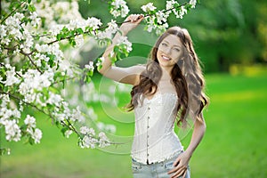 Young spring fashion woman in spring garden Springtime Summertime Trendy girl in the flowering trees in the spring summer garden