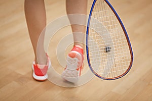 A young squash player hiting a ball in a squash court