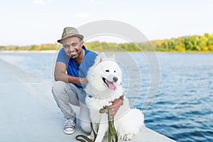 The young Sri Lankan and his fluffy dog have a rest in the park on the river bank.