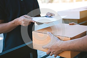 Young staff delivery man of the parcel carrier is submitting the documents to the customers to receive at home