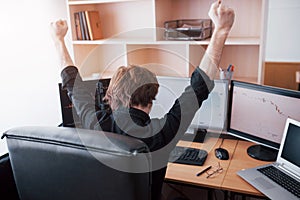 Young stock trader broker stretching hands at workplace, he first achieved great success on the stock market
