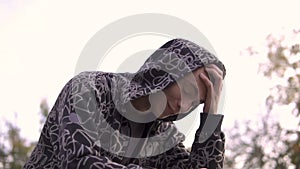 Young streetstyle man in hoodie Laughting while using his smartphone in hood, Sitting on the fence of skatepark