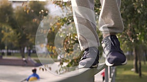 Young streetstyle man walk by railing on the border of skatepark in autumn city.