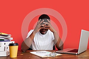 Young stressed african male working with computer laptop in frustration, depression