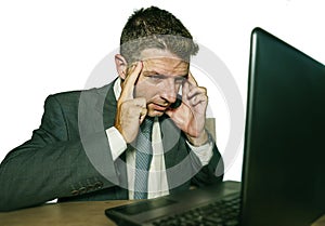 Young stressed businessman in suit and tie working overwhelmed at office laptop computer desk suffering headache cause of work