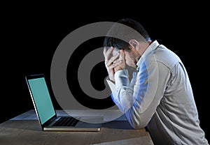 Young stressed businessman working on desk with computer laptop in frustration and depression