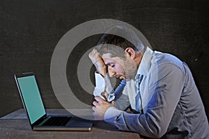 Young stressed businessman working on desk with computer laptop in frustration and depression