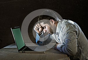 Young stressed businessman working on desk with computer laptop in frustration and depression