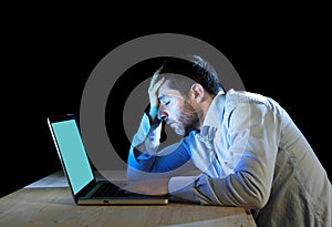 Young stressed businessman working on desk with computer laptop in frustration and depression