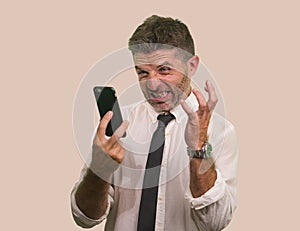 Young stressed and upset businessman in shirt and necktie working using mobile phone checking online business overwhelmed and