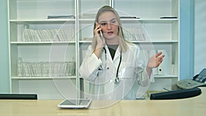 Young stressed woman yelling and gesturing while speaking on telephone at hospital reception