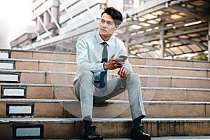 Young Striving Asian Businessman Sitting on Staircase in the City photo