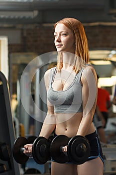 Young strong girl do exercises with dumbbells