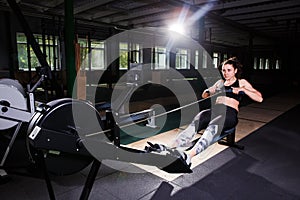 Young strong girl doing an exercise on a rowing machine. For training cardio arms, back. Sporting concepts