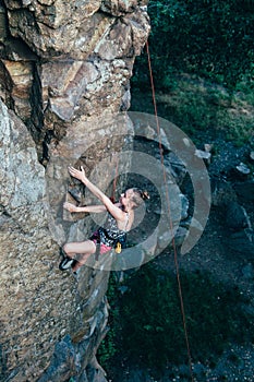 Young slender climber climbs a rock