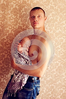 Young strong man holding a small fragile baby in her arms