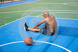 Young strong man, male basketball player practicing at street public stadium, sport court or palyground outdoors