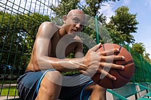 Young strong man, male basketball player practicing at street public stadium, sport court or palyground outdoors