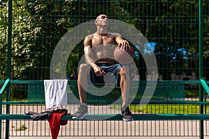 Young strong man, male basketball player practicing at street public stadium, sport court or palyground outdoors