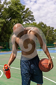 Young strong man, male basketball player training at street public stadium, sport court or palyground outdoors. Concept