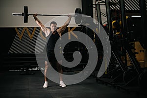 Young strong man with perfect beautiful body wearing sportswear lifting heavy barbell from floor