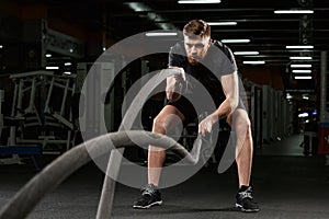 Young strong sports man make sport exercises in gym