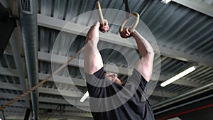 Young strong sportsman doing handstand on gymnastic rings in gym indoors. Portrait of handsome Caucasian bearded man