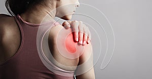 Young strong sporty woman suffering from pain in shoulder in sport wear. Touching the hand. Sports exercising injury. Closeup photo