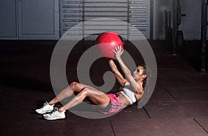 Young strong sweaty fit muscular girl with big muscles doing sit ups with medicine ball for abdominal muscles or abs hard workout