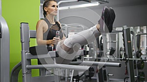 Young strong woman with perfect fitness body in sportswear exercising abdominals in gym. Girl training - lifting legs