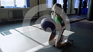 Young strong woman with perfect fitness body in sportswear exercising with medicine ball at gym. Girl doing crossfit