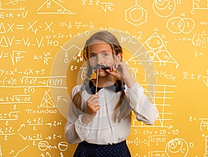 Young student acts like a senior teacher and wants to solve an advance math problem. Yellow studio background