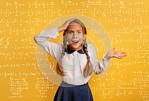 Young student is amazed about the difficulty of math problem. Yellow studio background