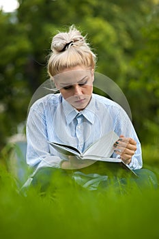 Young student girl reading a book in park