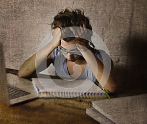 Young student girl studying late night tired at home laptop computer preparing exam exhausted