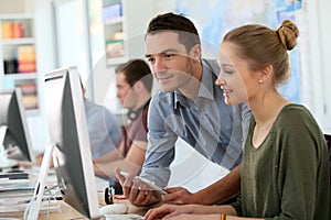 Young student girl with teacher working on a computer