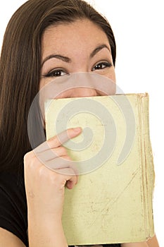 Young student laughing behind a book covering her face