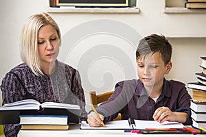 Young student learns at home with a his mom tutor. Helping.