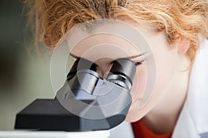 A young student looking into a microscope