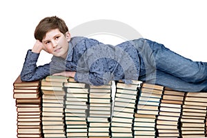 A young student lying on a stack of books