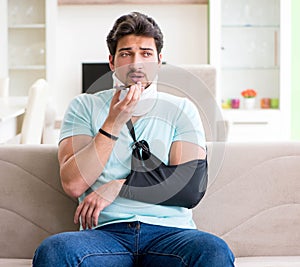 Young student man with neck and hand injury sitting on the sofa